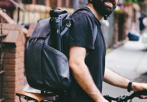 Man carrying a Peak Design Tripod in his backpack while traveling on a bike